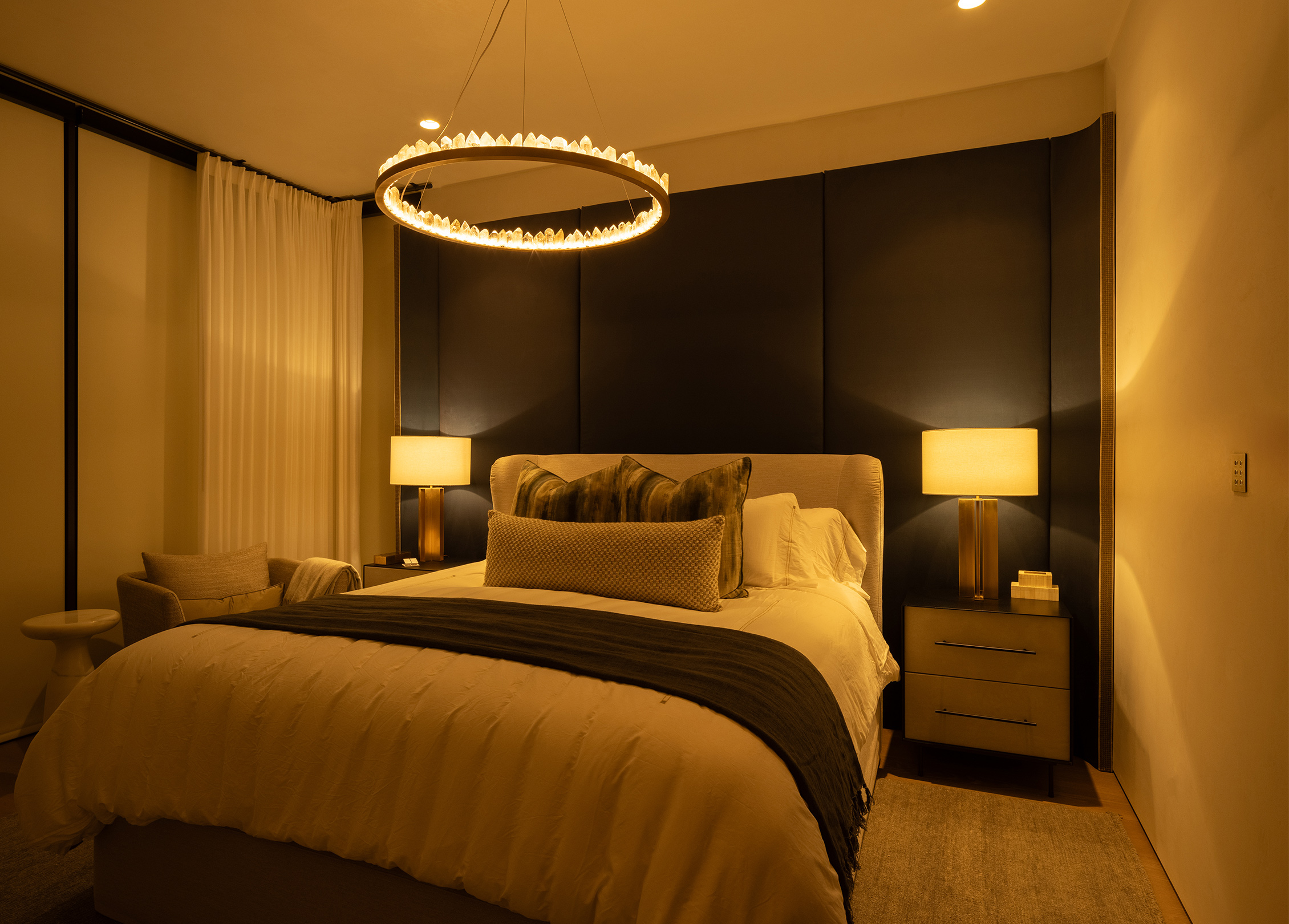 Nighttime bedroom lighting scene featuring roller shades, drapes and warm decorative lighting at Stay Bungalow