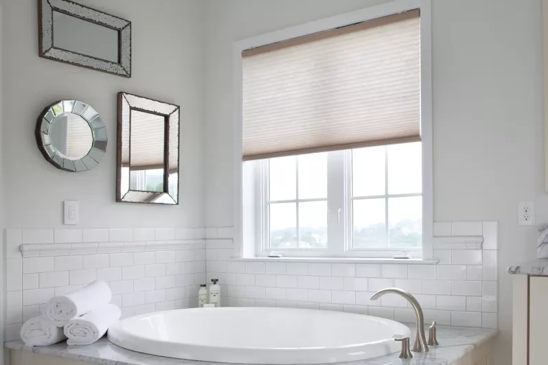 Automated cellular shades in bathroom setting provide privacy while allowing natural light through light-filtering fabrics