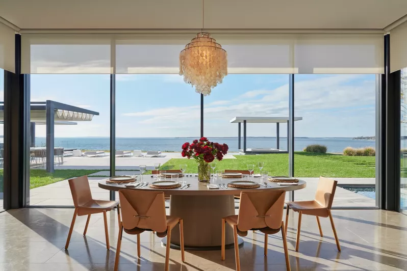Chandelier and roller shades in dining room balancing view preservation and daylight control